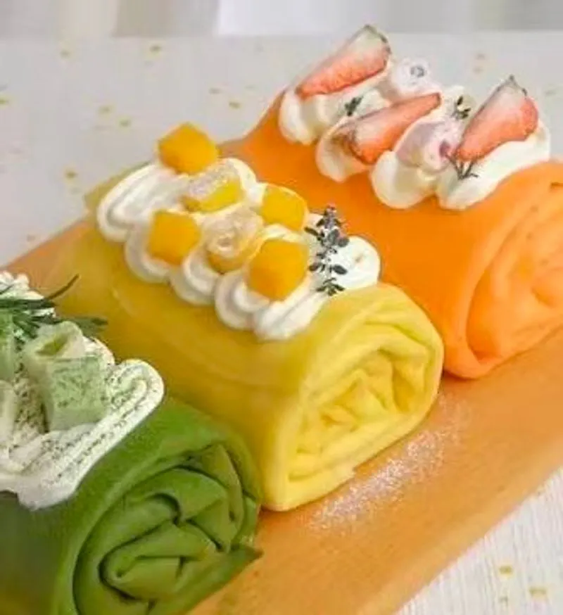 Three colorful fruit crepe rolls topped with mango, strawberry and matcha cream at Mrs Hen Tea & Bites, a Bubble Tea Shop in Flushing